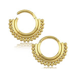 The Gold Septum Clicker 16g - 8mm by Kaya Movement is a beautifully designed piece of piercing jewelry. It features intricate detailing with a series of small, rounded gold beads along the outer edge, offering a traditional and elegant appearance. This symmetrical design makes it a perfect complement to any gold body jewel collection. The image is presented on a white background.