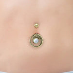 A close-up of a belly button adorned with Kaya Movement's Belly Button Teardrop Piercing Jewelry With Mother Of Pearl. The gold navel ring features a 14g stud at the top and a larger teardrop piece below, showcasing intricate detailing and an organic marquise design centered around a gem resembling Mother Pearl. The smooth, well-cared-for skin adds to the jewelry's elegance.