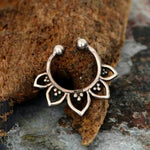 Close-up of the intricate Fake Septum "Solara" 925 Silver Mandala by Kaya Movement, showcasing an elegant mandala design with petal-shaped extensions adorned with tiny bead details. The no-pierce nose jewelry is placed on a textured, natural surface, adding a rustic background to highlight the piece.