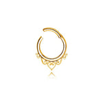 The Minimalist Mandala-Inspired Septum in 316L Steel PVD Gold "Zura" by Kaya Movement features intricate detailing at the bottom, including a small center heart surrounded by symmetrical loops and curls. Crafted from high-quality 316L steel, it has a small opening at the top for easy insertion. This gold-finish septum ring is available in 1.2mm gauge with diameters of 6mm, 8mm, and 10mm.