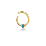 The Oriel Minimalist Gold PVD 316L Stainless Steel Septum with Blue Opal from Kaya Movement is displayed against a white background. This sleek, small, gold circular earring features intricate beaded detailing and a clasp at the top. Centered at the bottom of the circle, there's a blue opal gemstone encased in the gold setting. The minimalist jewelry piece designed for nose, tragus, or lobe appears to be partially open.