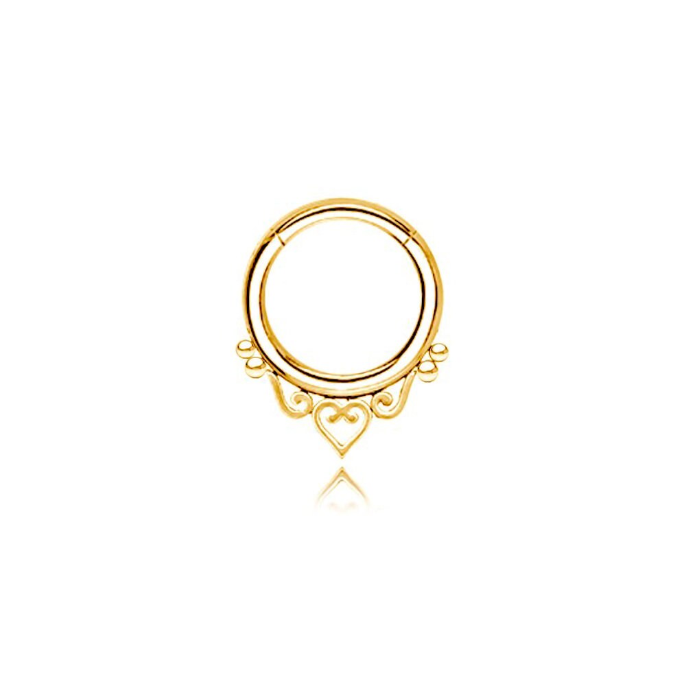 The Minimalist Mandala-Inspired Septum in 316L Steel PVD Gold "Zura" by Kaya Movement showcases a beautifully intricate heart and swirl design at the bottom. This circular septum ring, available in 1.2mm gauge and diameters of 6mm, 8mm, and 10mm, features delicate detailing that adds an elegant touch to the jewelry piece. Set against a white background, it perfectly captures the mandala-inspired charm.