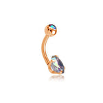 The Kaya Movement Aurora Navel Jewelry features a rose gold finish curved barbell with a small ball on one end and a larger, multi-faceted heart-shaped aurora borealis crystal on the other, displaying a rainbow of colors. Shown against a plain white background, this elegant piece is crafted from 316L surgical steel.