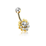 The Zane 1.6mm Navel Piercing by Kaya Movement features a brilliant gold finish and a curved barbell design. One end of the barbell showcases a clear zircon gem, while the other end displays a circular cluster of seven sparkling zircons forming an elegant flower shape, with a larger central gem surrounded by smaller ones for added luxury.