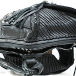 Close-up of the APOPHIS Post-Apocalyptic Leather Shoulder & Belt Bag by Kaya Movement featuring a zippered opening. The black leather bag showcases textured, folded sections with leather tassels hanging from the top. The material appears rugged and slightly worn, complemented by glossy finishes in certain areas, making it an ideal accessory for an apocalyptic hip bag or wasteland festival look.