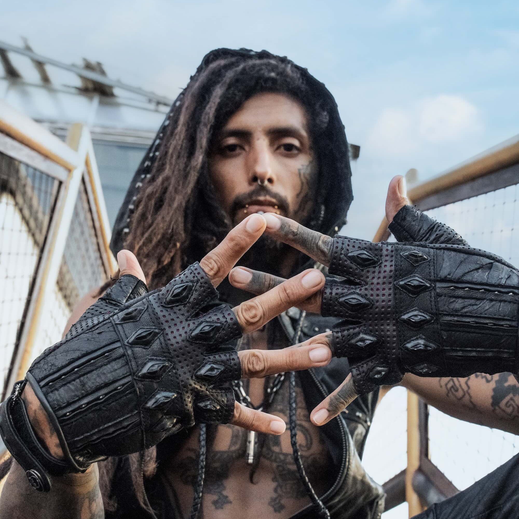DZALA — black leather fingerless gloves with studs and red accents.