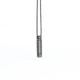 A side-angle view of the same futuristic pendant, showcasing its intricate linear patterns and metallic detailing, suspended from a cord.