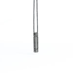 A side-angle view of the same futuristic pendant, showcasing its intricate linear patterns and metallic detailing, suspended from a cord.