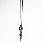 Artistic shot of the biomechanical pendant laying on a white background, emphasizing its sculptural and industrial style.