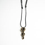 Artistic shot of the biomechanical pendant laying on a white background, emphasizing its sculptural and industrial style