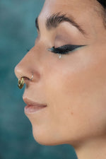 Close up artistic shoot of a women wearing a gold septum clicker with garnet stone