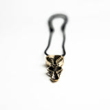 Close-up of the brass spoon pendant, highlighting its biomechanical details and the smooth, polished finish.