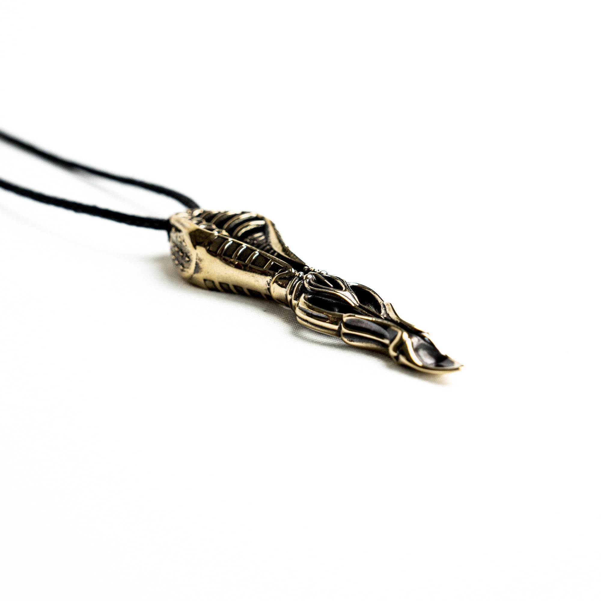 Intricate brass pendant with skeletal motifs and fluid lines, showcasing a sci-fi and dystopian design influence.
