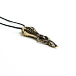 Intricate brass pendant with skeletal motifs and fluid lines, showcasing a sci-fi and dystopian design influence.