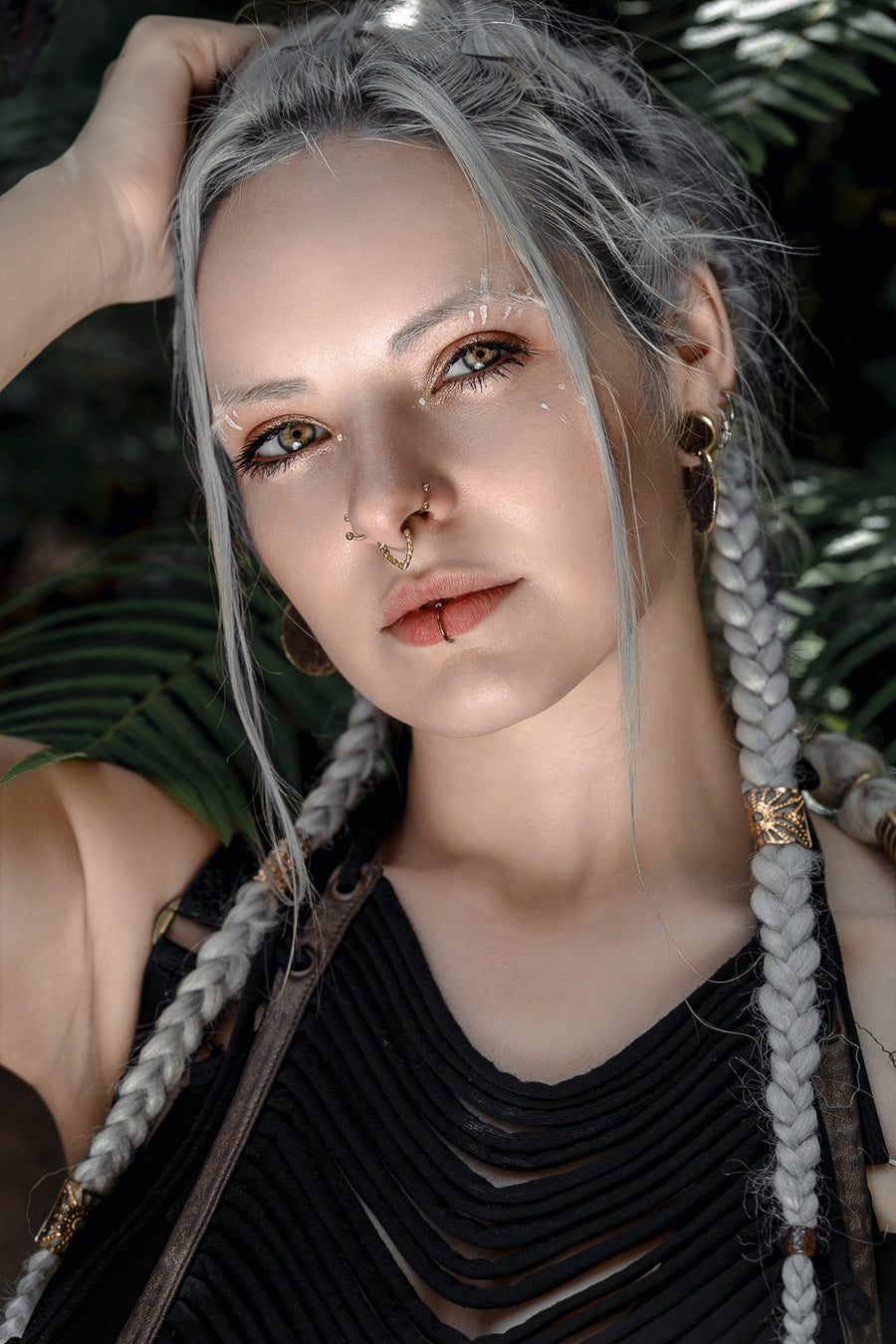 V-shaped septum piercing, alien bio-organic design, platinum blonde hair, leafy backdrop, distinctive statement piece, avant-garde body art.