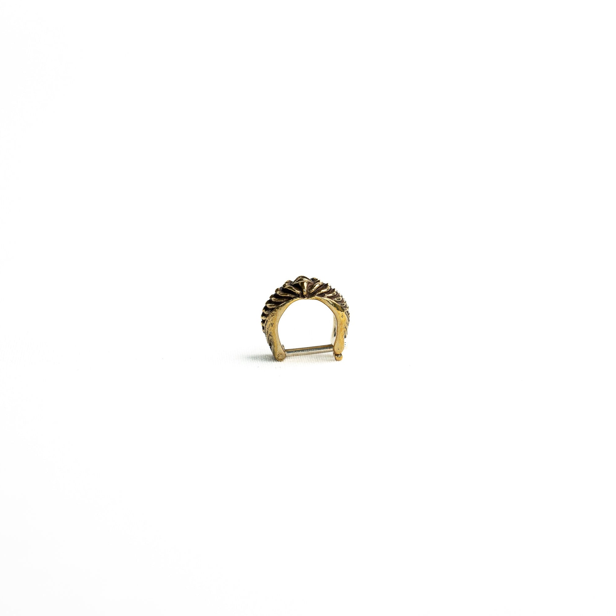 A front-angle view of a brass bio-organic septum ring with a clicker closure, showing its smooth curvature and antique finish.