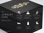 A black jewelry box branded with Kaya Movement featuring gold text and logo on the lid. The text reads "Jewelry Care" with tips: Remove before showering, swimming, going to the beach, sauna, physical activities. Avoid sleeping in jewelry and keep it away from chemicals. Store TRAKARA Heavy Tribal Cyborg Clicker Ear Weights in Gold | 2 gauge and other post-apocalyptic body jewelry in the box.