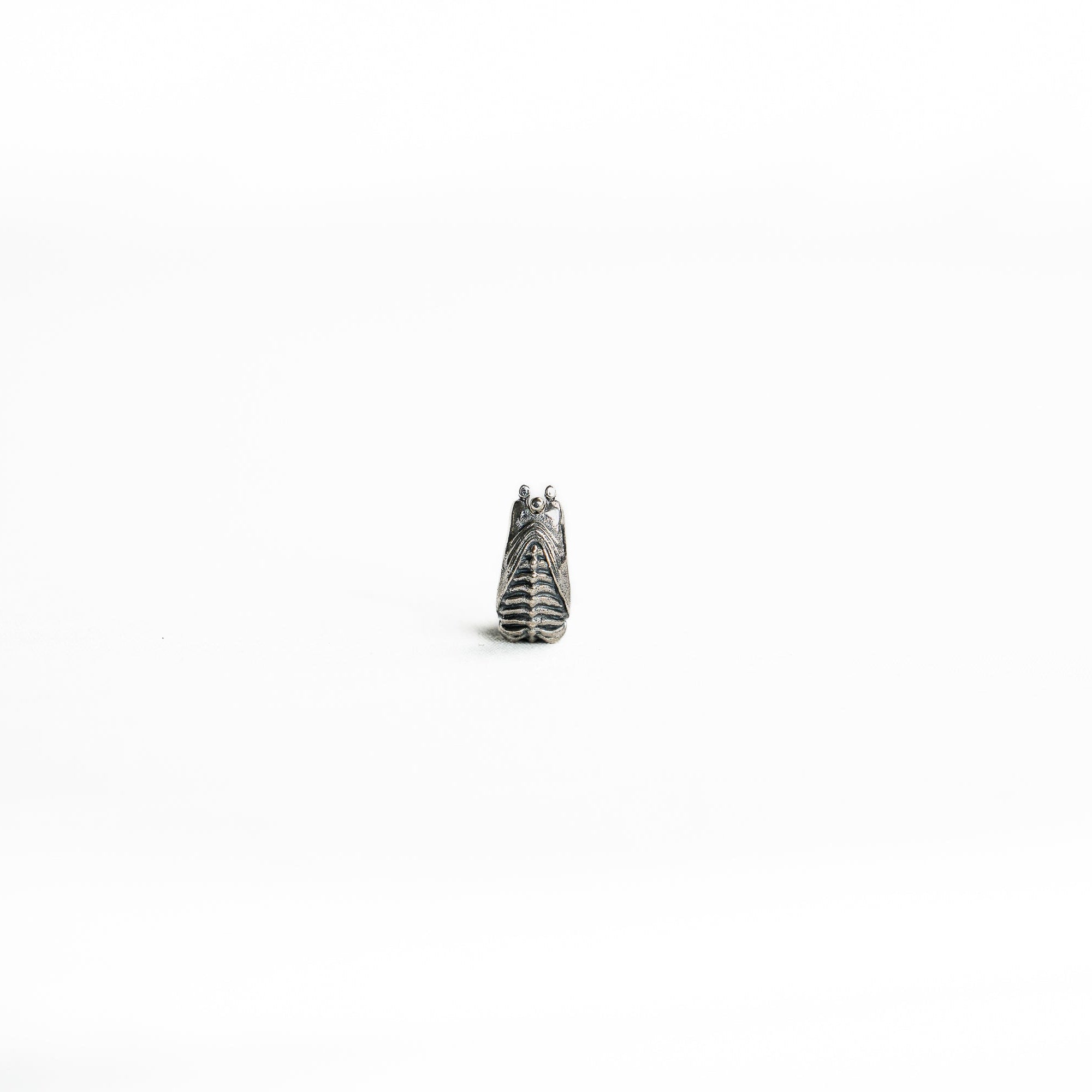 A vertical view of the silver biomechanical septum clicker, focusing on its detailed ridges and symmetrical design.