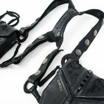 Close-up of the KERO Unisex Lightweight Leather Holster Bag from Kaya Movement, crafted from premium sheep skin leather. This holster bag showcases intricate stitching and metallic embellishments. The design features straps adorned with round, silver-toned studs and metal accents, complemented by visible zippers on attached pouches. Perfect as an accessory for the Burning Man festival. The background is a plain white surface.