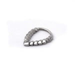 The Kaya Movement KAMO Biomech Teardrop Clicker Septum Ring in Silver | 16 gauge is a uniquely designed, handcrafted piece of body jewelry. It features a sequence of small geometric shapes that create a gradient-like pattern, starting with smooth, rounded forms on one end and transitioning to textured, angular shapes on the other, forming an elegant teardrop shape.