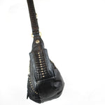 Introducing the Nebula Unisex Leather Off Shoulder Cross Body HandBag by Kaya Movement, a custom leather goods creation. This black leather shoulder bag is adorned with gold studs and decorative stitching. Its thick, textured strap allows the black leather bag to dangle strikingly against a plain white background, making it an ideal accessory for those seeking unique pieces at dystopian festivals.