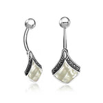 The IKOWA Marquise Belly Piercing Rings by Kaya Movement feature a curved barbell design in silver, with intricate patterned detail and a Mother of Pearl inlay. Each 14-gauge piece of navel jewelry is crafted from surgical steel and includes spherical ends, adding an elegant touch to the design.