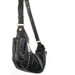 Image of the Nebula Unisex Leather Off Shoulder Cross Body HandBag by Kaya Movement. This custom black leather bag features a wide strap adorned with gold studs and decorative stitching. It also includes a flap with a gold button and intricate front details, such as metallic diamond-shaped accents. Perfect for events like dystopian festivals, where bold style is essential.