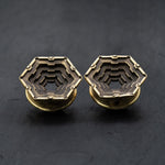 A pair of Kaya Movement's HEXA Futuristic Geometry Hexagon Flesh Tunnels in gold, available in sizes ranging from 12mm to 24mm, featuring an intricate and layered geometric design. Reminiscent of visionary AI plug earrings, the flesh tunnels are positioned side by side on a dark, textured background.