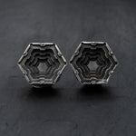 Introducing the HEXA Futuristic Geometry Hexagon Flesh Tunnels in Silver by Kaya Movement. These intricate, hexagonal metallic tunnels feature a three-dimensional stepped design set against a dark background. Their modern, geometric style makes them perfect for those with stretched ears or as unique body jewelry; the oxidized metal finish adds a slightly aged look. Available in sizes ranging from 12mm to 24mm.
