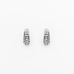 The AARO Cyborg Clicker Hoop Ear or Septum Weights from Kaya Movement are a pair of small, pendant-style earrings made of 925 silver, featuring a textured, scalloped design. Each earring boasts an elongated teardrop shape and intricate detailing that gives them a vintage, artisanal appearance. These 6-gauge weights are perfect for those with stretched ears or as a complement to a septum piercing. The background of the product image is plain white.