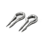 Close-up view of two CALYPSO Minimalist Keyhole Ear Weights in 925 Silver by Kaya Movement, each in a 2 gauge size. They feature a narrow, elongated U shape with two pointed prongs at the ends. The weights have a slightly rough, worn surface and are placed against a plain white background, resembling futuristic jewelry designed for stretched ears.