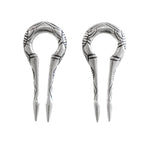A pair of EXRO Biomechanical Cyborg Keyhole Ear Weights in 925 Silver by Kaya Movement, designed with a circular top and two pointed prongs, echoing the craftsmanship of unisex gauge earrings. The ear weights feature an intricate ornamental pattern and are displayed side by side against a white background.
