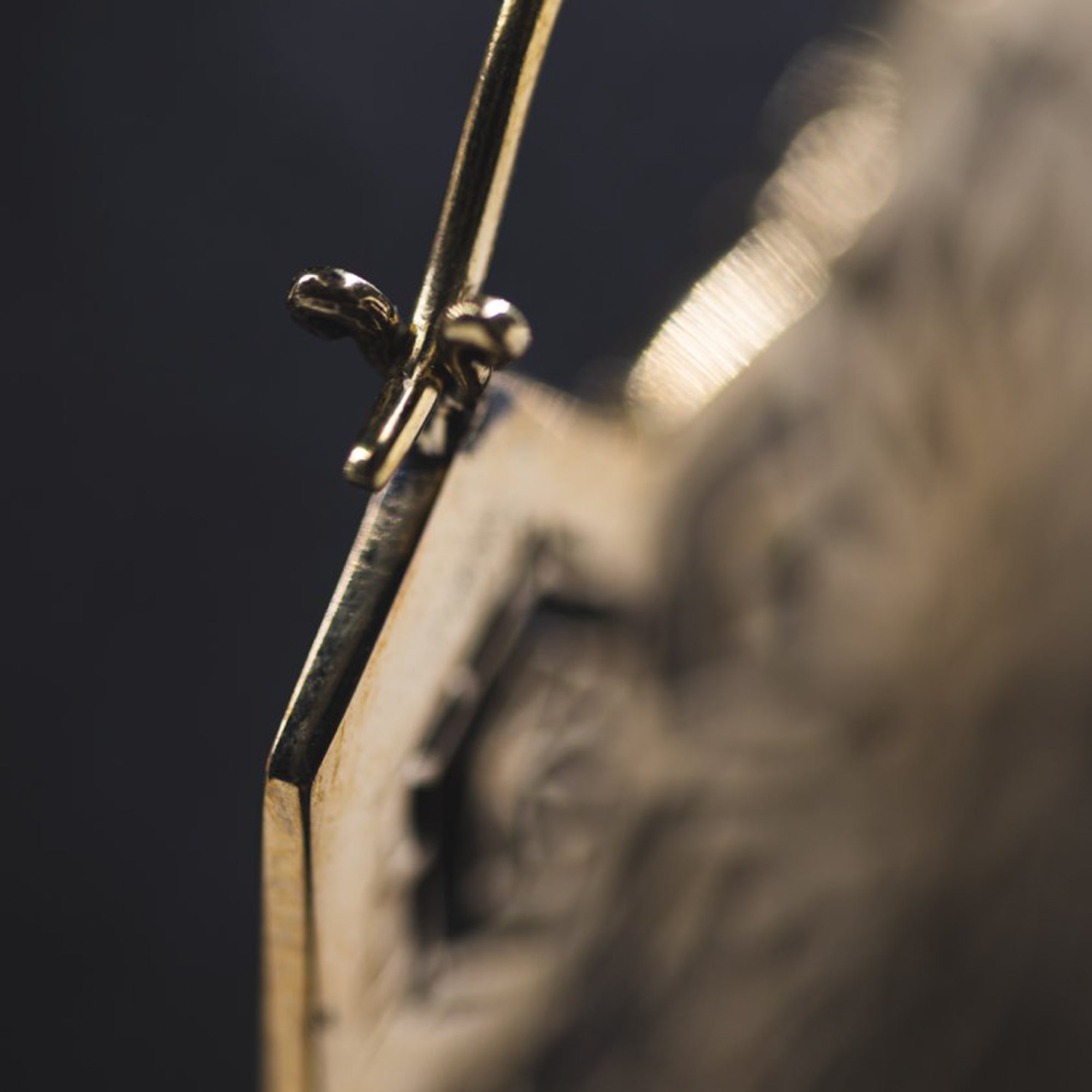 Close-up image showcasing a section of the ASA Oversized Asa No Ha Mandala Disc Earrings in Gold by Kaya Movement, highlighting the thin 16-gauge wire-like structure and small clasp mechanism. The focus is on the intricate tribal-inspired details, with an out-of-focus background that enhances the emphasis on the fine craftsmanship.