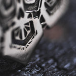 Close-up image of Kaya Movement's ASA Oversized Asa No Ha Mandala Disc Earrings in Silver | 16 gauge, showcasing their intricate Asanoha motif on a rough, dark surface. The focus is on the detailed design, highlighting the texture and craftsmanship. The background is blurred, emphasizing the earrings' sharp features.