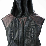 A detailed view of the VENOM Men's Leather Hooded Vest Jacket by Kaya Movement showcases its black leather construction with a textured surface. This sleeveless, hooded vest is adorned with intricate stitching and features dark mesh-like panels on the shoulders, along with decorative diamond-shaped embellishments down the center. Its red lining adds a striking contrast, making it perfect for fans of custom leather goods.
