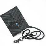 Introducing the AMONI Black Stud Bi-Fold Flip Leather Wallet by Kaya Movement. This handcrafted black leather wallet showcases intricate stitching and scale-like patterns, highlighted by a stunning blue labradorite gemstone on the front. Reminiscent of a designer leather pouch, it features a braided leather cord with a metal clasp for an added touch of elegance. Set against a white background, this piece is perfect for anyone appreciating fine craftsmanship.