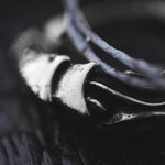 Close-up image of the PROMETHEUS Small Cyborg Hoop Earrings by Kaya Movement, crafted from 925 silver with an 18 gauge thickness. The metallic earrings feature curved and textured surfaces, with a dark, out-of-focus background that accentuates the bright, reflective edges of the intricate design.