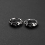 A pair of intricately designed PROMETHEUS Small Cyborg Hoop Earrings 925 Silver by Kaya Movement is displayed on a black background. The earrings feature twisted and detailed metalwork, creating a unique and stylish appearance with a slightly oxidized finish for a vintage look, evoking the allure of sci-fi statement earrings.