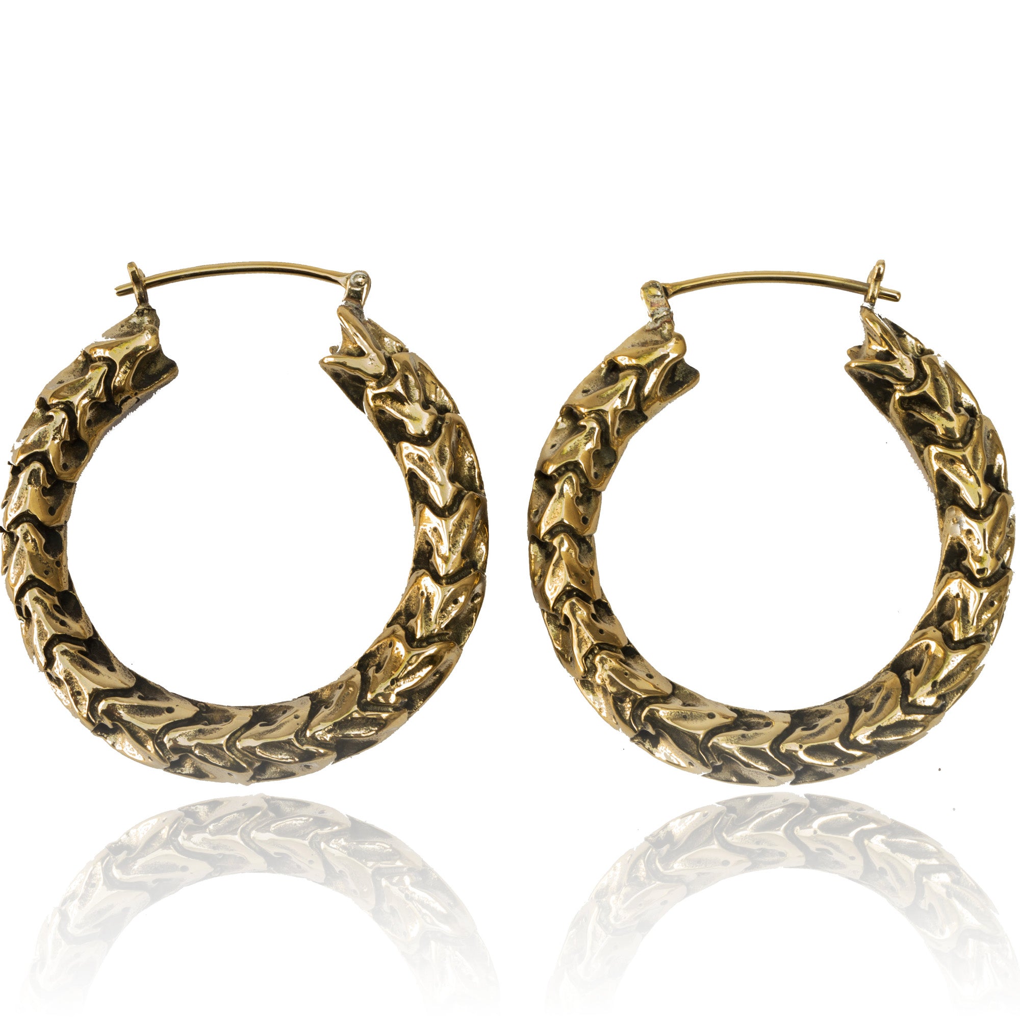 The QUETZALCOATL Oversized Snake Spine Hoop Earrings in Gold by Kaya Movement are crafted in a textured, wavy pattern. The hoops are shown standing upright with their hooks visible at the top. These 14 gauge sci-fi statement earrings have a glossy finish that reflects light and are displayed against a white background.