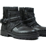 Introducing the MAGMA Wasteland Studded Leather Ankle Combat Boots by Kaya Movement. These black leather punk rock boots boast a rugged design with striking details such as straps, studs, and textured fabric panels. Featuring a chunky tread sole and side zippers for closure, they seamlessly blend style with functionality.