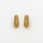The TRILOBITE Small Biomechanical Clicker Ear Weights in Gold Brass by Kaya Movement are displayed against a white background. These earrings feature a design with multiple horizontal ridges, giving them a ribbed appearance. These stunning pieces embody the essence of post-apocalyptic body jewelry with their rugged yet refined texture.