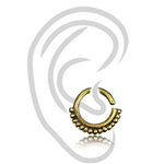 The IRI Seamless Tragus Ring in Gold by Kaya Movement is an 18 gauge yellow brass ear cuff showcasing a half-circle design with intricate beaded detailing along the bottom edge. Set against a transparent background with a gray ear illustration, this piece of body jewelry imbues a touch of tribal ethnic charm.