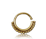 The IRI Seamless Tragus Ring in Gold by Kaya Movement is an 18 gauge gold nose ring featuring an open loop design, adorned with a row of small gold beads along the bottom half. Its smooth finish and reflective surface highlight its tribal ethnic design, making it perfect as body jewelry, elegantly displayed against a plain white background.