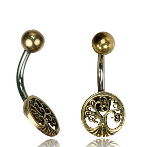 The Tree of Life Belly Piercing Ring in Gold by Kaya Movement is a pair of 14 gauge curved navel barbells featuring a gold-colored ball on one end and an intricately designed tree of life with ornate, swirling branches on the other, adding a decorative touch to the surgical steel jewelry.