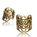 Two Kaya Movement "Flower of Life" gold ear cuffs with intricate, openwork designs. The closer cuff displays the iconic Flower of Life pattern, while the other showcases a similar design from a different angle. Both reflect light, emphasizing their shiny and delicate craftsmanship against a white background.