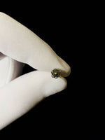 A gloved hand holding a small, intricately designed Kaya Movement Flower nose stud against a black background. The Silver 925 bead is circular with a floral pattern, featuring a central raised dot.