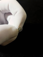 A gloved hand holds a small, intricately designed Kaya Movement Flower nose stud. The Silver 925 nose stud features a delicate stone or bead in the center and boasts a beautiful floral mandala pattern. The dark background highlights its exquisite details, showcasing the craftsmanship beautifully.