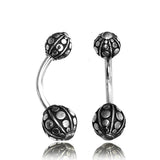 The GEO Globe Belly Piercing Ring by Kaya Movement features a pair of curved barbell piercings in silver, made from 14 gauge surgical steel. Each piece is adorned with decorative balls on both ends, showcasing intricate circular and dot patterns that add texture and ornateness. Perfect for navel jewelry, they come in elegant gift packaging.