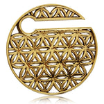 A golden circular pendant, reminiscent of Kaya Movement's FLOWER OF LIFE Disc Ear Weights in Gold, showcases an intricate openwork design that blends interlocking flowers and geometric shapes. This elegant piece also features a small circular cut-out near the top left.