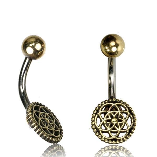 Introducing the Flower of Life Belly Piercing Ring in Gold by Kaya Movement. This 14 gauge decorative belly button ring features a spherical gold top paired with a hanging charm that showcases an intricate circular, mandala-like design. The body of the ring is expertly crafted from surgical steel, creating a striking contrast with the gold elements. Be sure to refer to our size guide for the perfect fit.